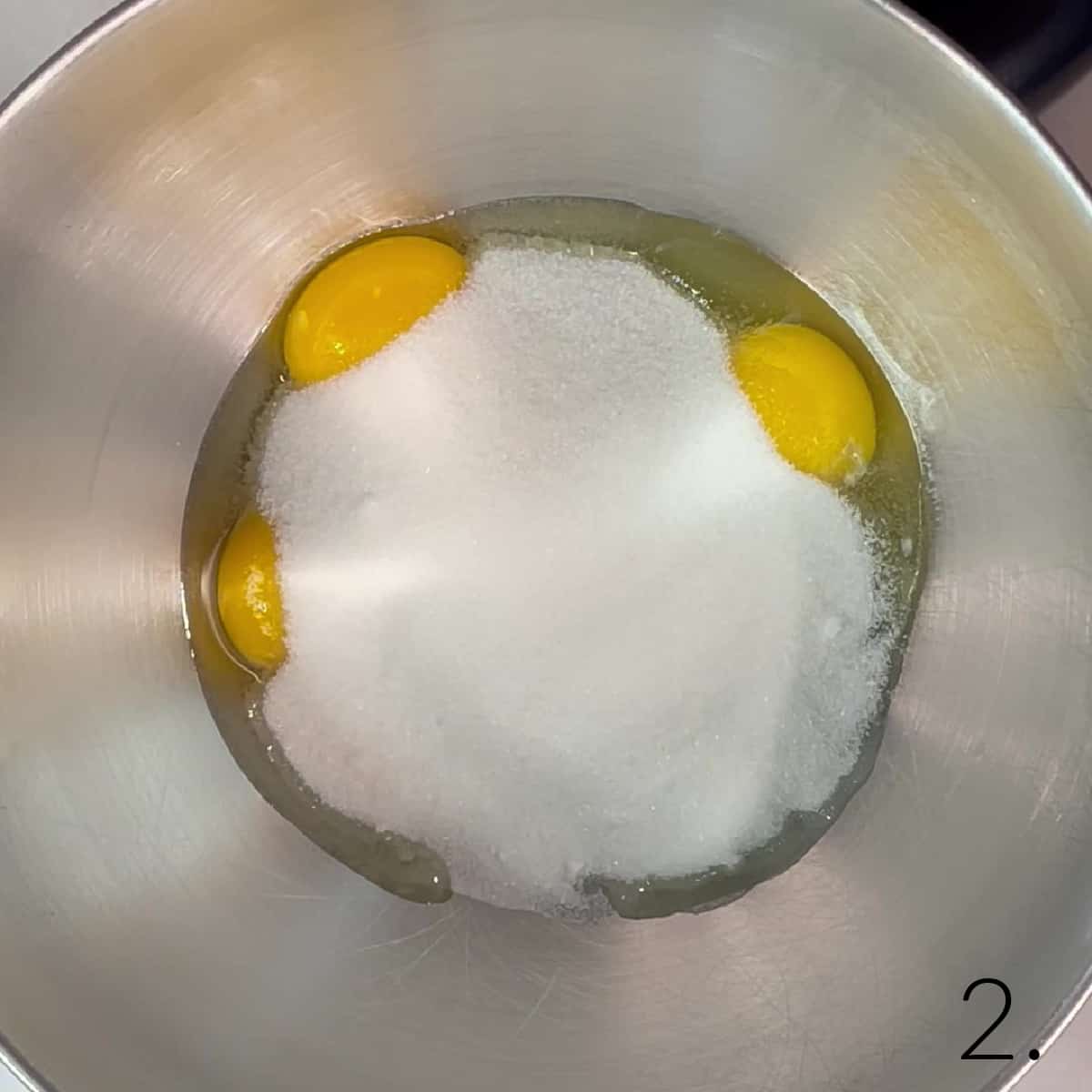 Eggs and sugar in a mixing bowl.