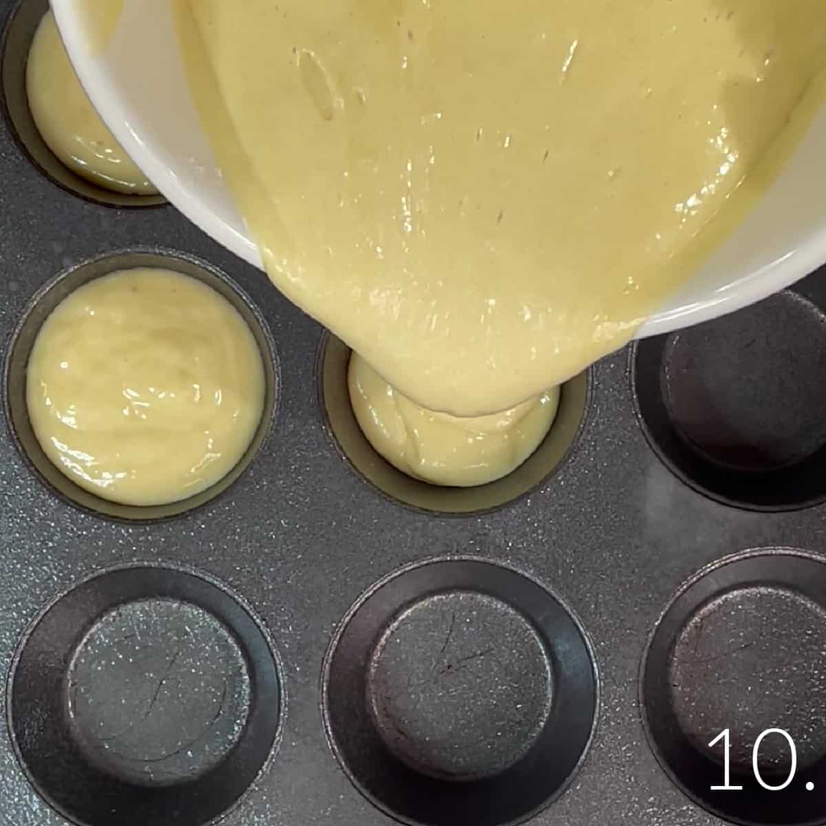 A bowl with a pour spout filling cupcake tins with batter for Boston Cream Cupcakes.