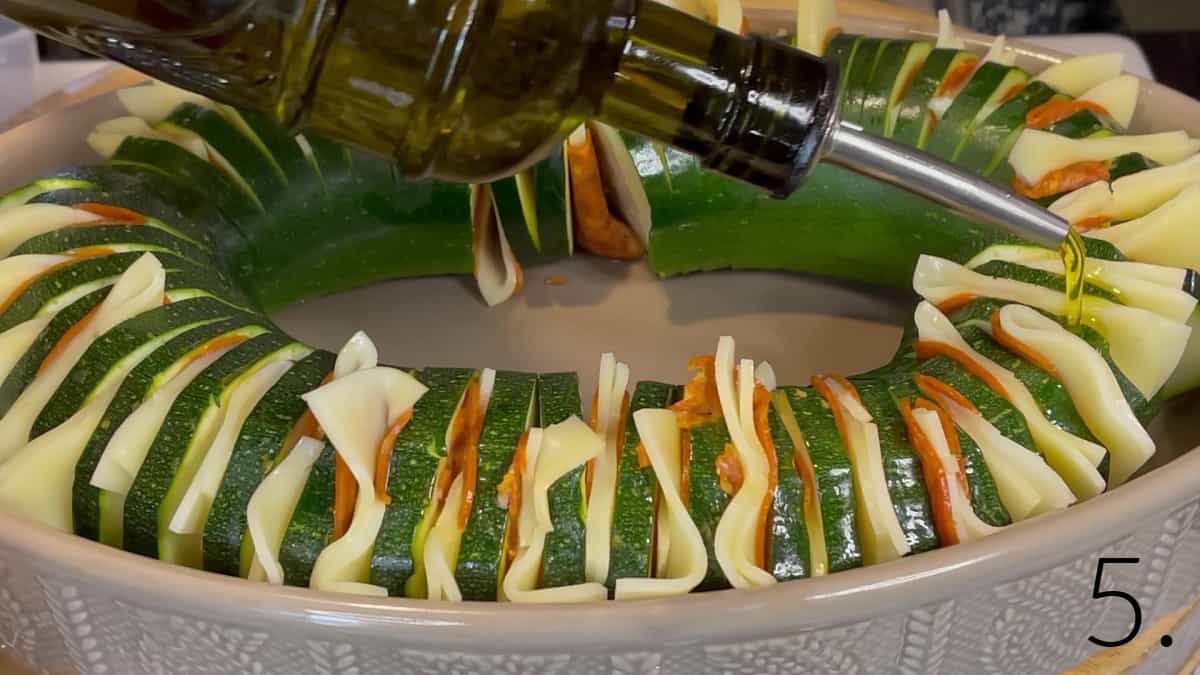 Olive oil being drizzled onto a Pepperoni Pizza Hasselback Zucchini before baking.