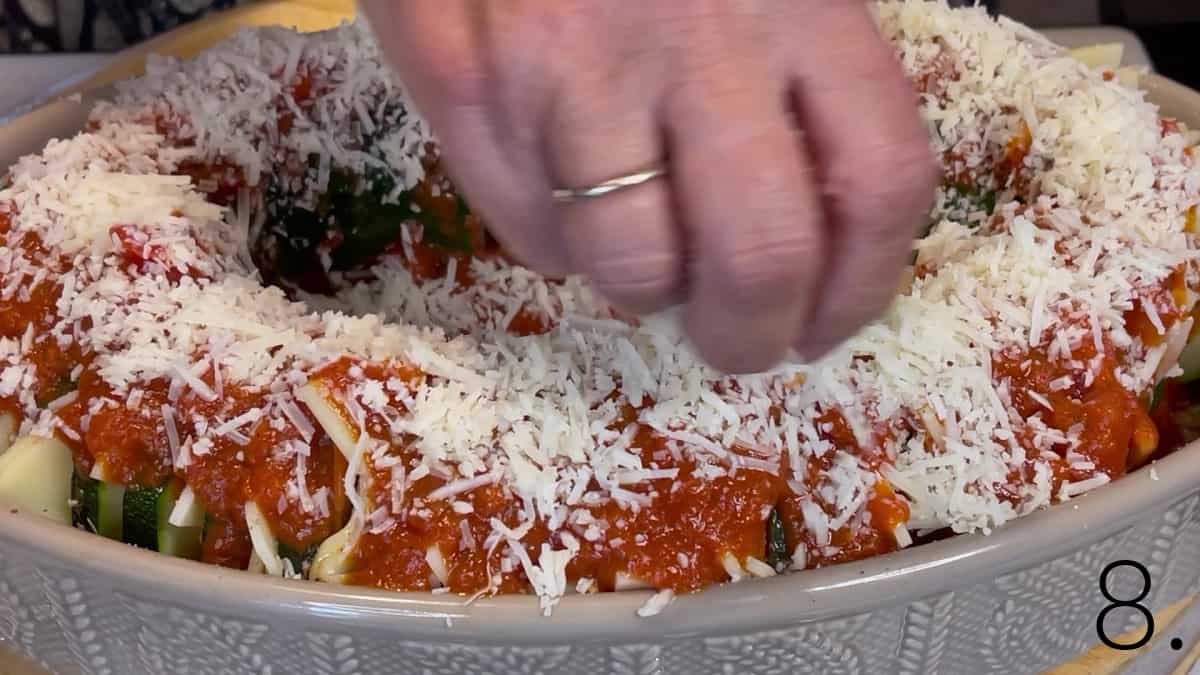 Grated Parmesan cheese being sprinkled over a Hasselback Zucchini.