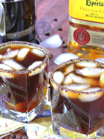 Two cocktail glasses filled with Iced Coffee Margaritas with a sugar and coffee rim.