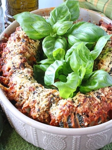 An oval casserole dish filled with Pepperoni Pizza Hasselback Zucchini topped with sauce and cheese.