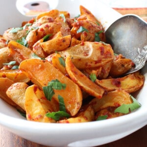 A white bowl filled with Roasted Baby Potatoes with Chili Garlic Paste and topped with parsley.