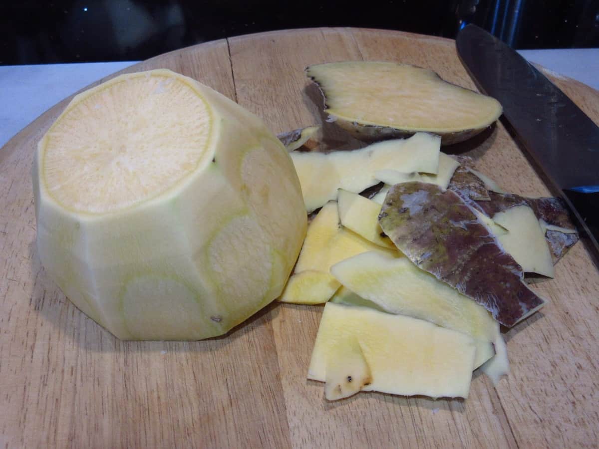 A whole rutabaga on a cutting board with all of the outer skin taken off.