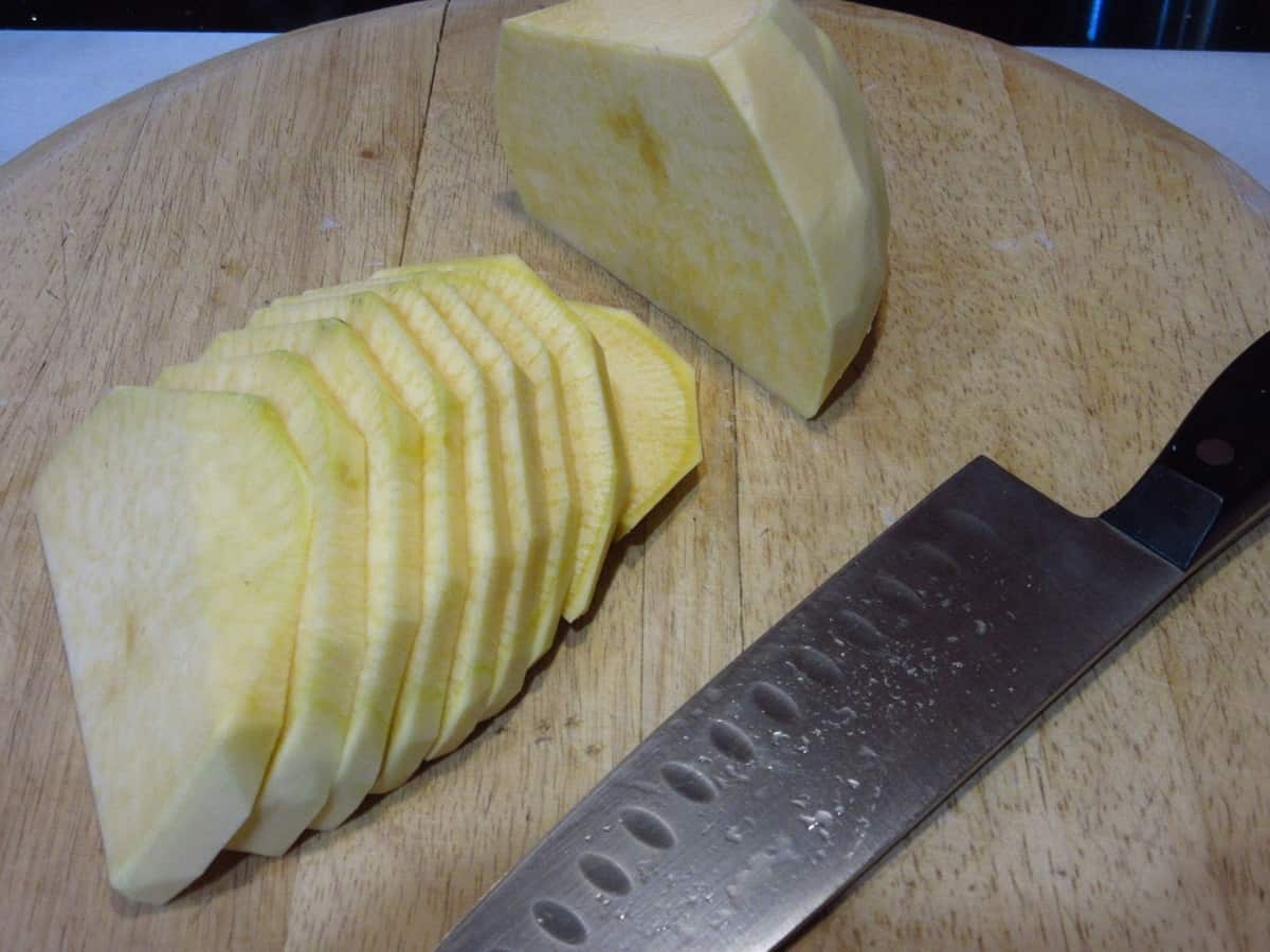 A peeled and sliced rutabaga on a cutting board.