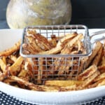 A oval white bowl along with a fry basket filled with golden brown Rutabaga Fries.