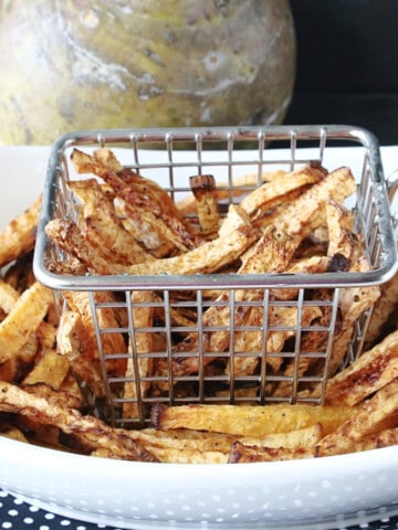 A oval white bowl along with a fry basket filled with golden brown Rutabaga Fries.