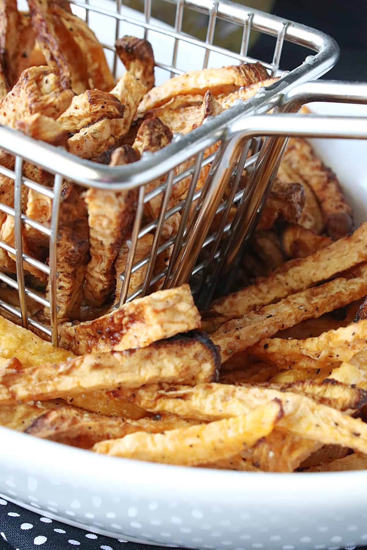 A closeup photo a some Rutabaga Fries in a wire basket.