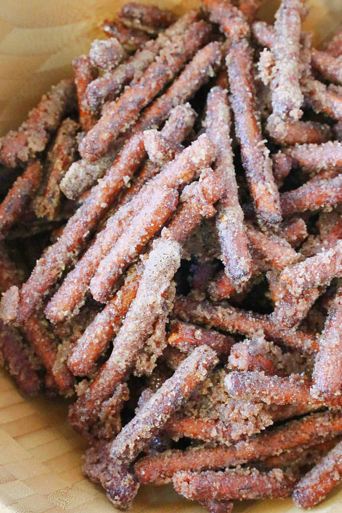 A bunch of pretzel sticks coated in cinnamon sugar in a wooden bowl.