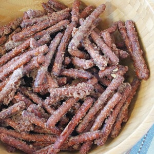 A bunch of pretzel sticks covered with cinnamon sugar in a wooden bowl.