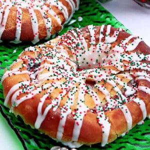 A Cranberry Kringle drizzled with icing and sprinkles on a green glass plate.