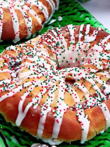 A Cranberry Kringle drizzled with icing and sprinkles on a green glass plate.