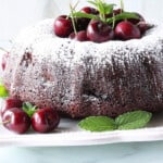 A pretty Chocolate Cherry Bundt Cake with fresh cherries and mint as garnish.