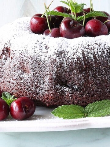 A pretty Chocolate Cherry Bundt Cake with fresh cherries and mint as garnish.