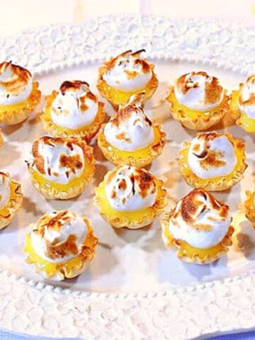 A bunch of Lemon Meringue Tartlets on a pretty white platter.