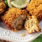 A closeup of the inside of a Muffin Tin Crab Cake with a cornflake coating on a pretty white plate.