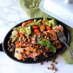 Two Salmon Fillets with Pistachio Basil Butter in a cast iron skillet topped with pistachios.