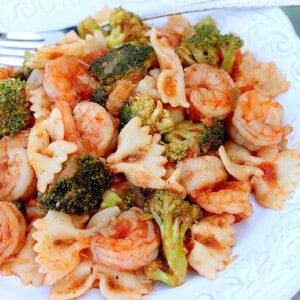 A serving of Shrimp Fra Diavolo on a plate along with bowtie pasta and broccoli.