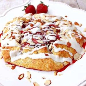 A pretty Strawberry Crostata with an almond glaze on a square white plate.