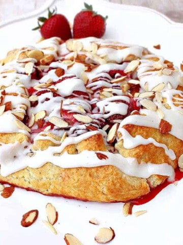 A pretty Strawberry Crostata with an almond glaze on a square white plate.