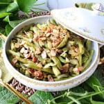 Bacon Bourbon Green Beans Almondine topped with almonds in a china serving bowl.