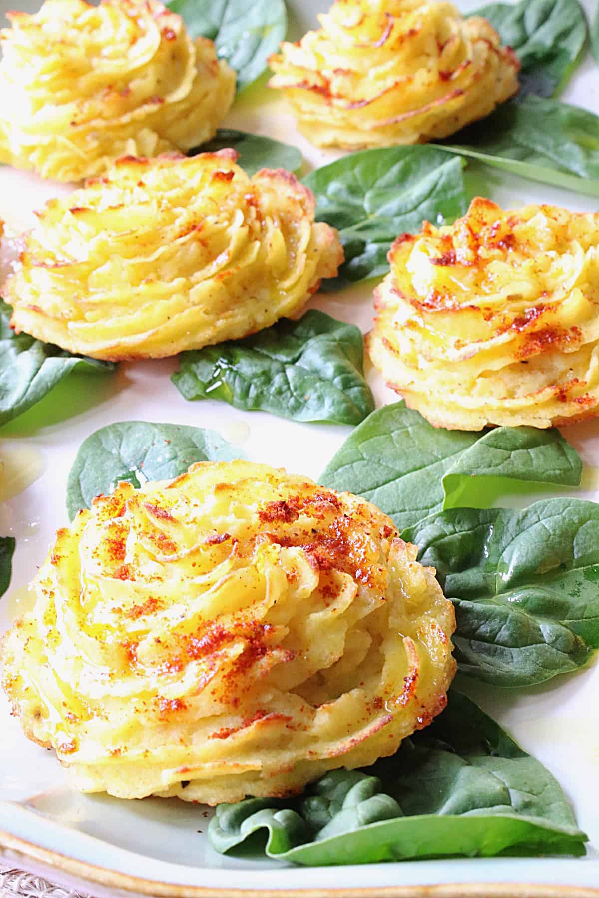 Golden yellow duchess potatoes with spinach leaves.