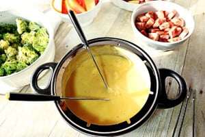 Creamy cheese fondue with fondue forks in a pot.