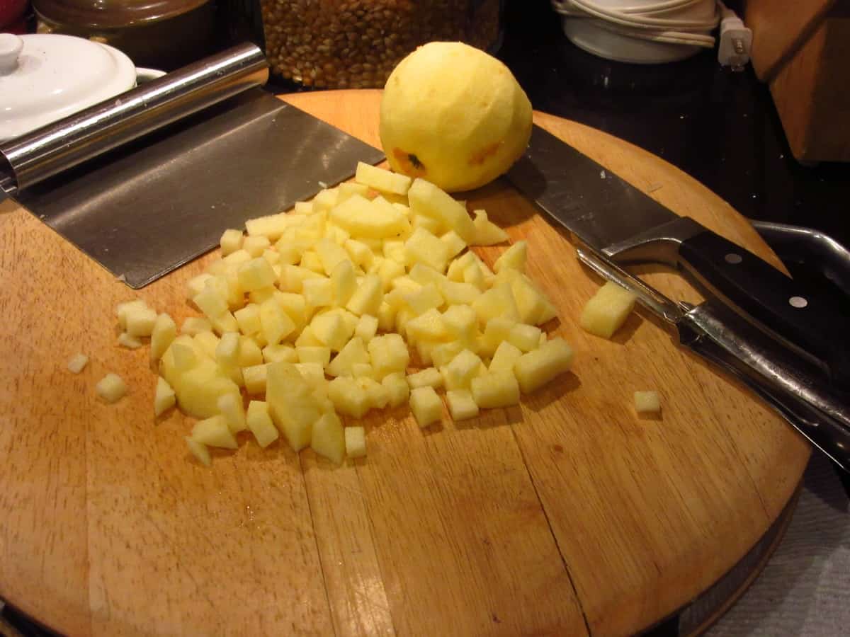 Cored and diced apples on a wood cutting board.