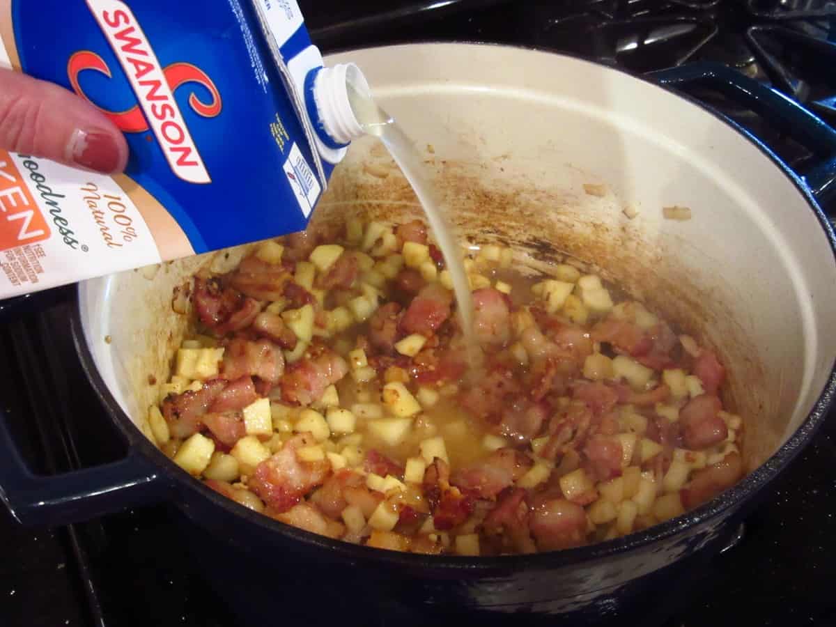 Chicken stock being added to a Dutch oven while making Apple Corn Chowder.