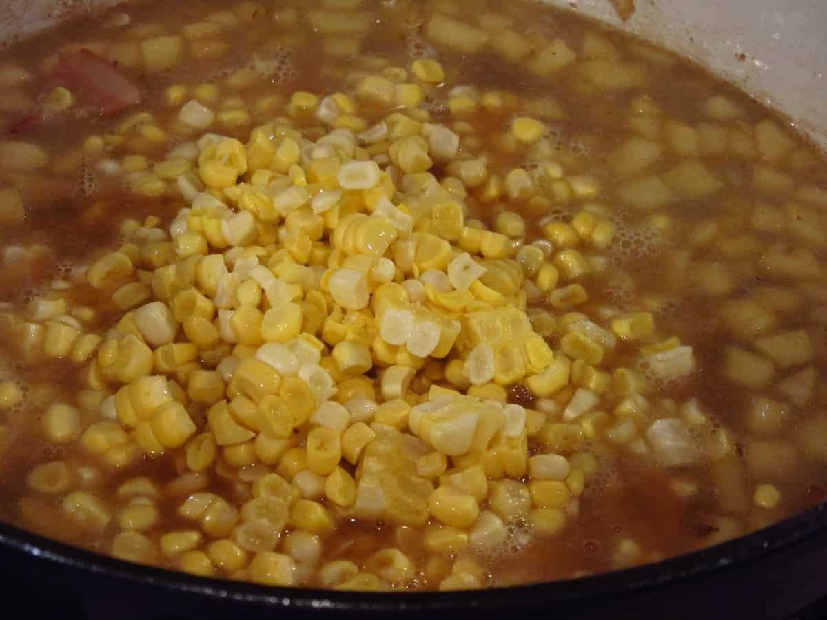 Corn and broth in a large pot for making apple corn chowder.