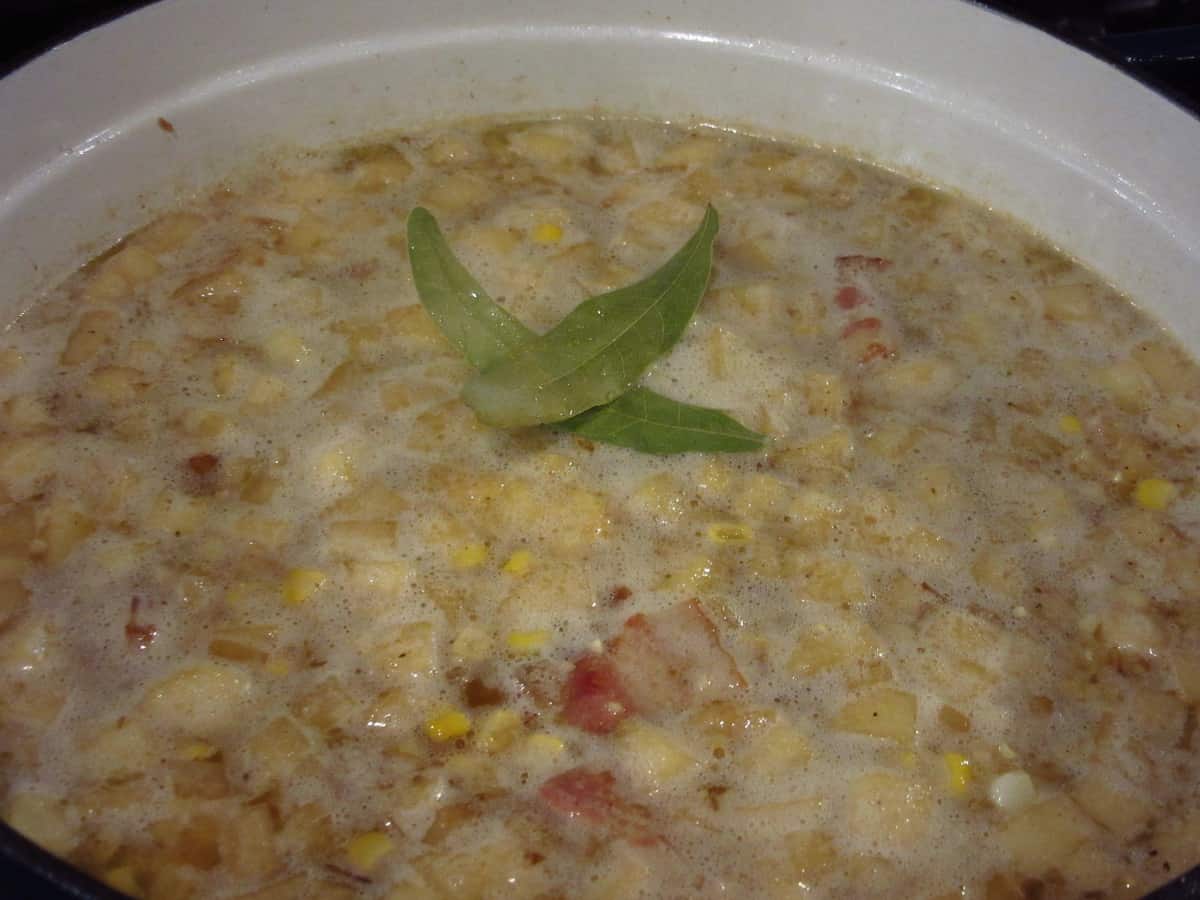 Two bay leaves in a hot pot of apple corn chowder with bacon.