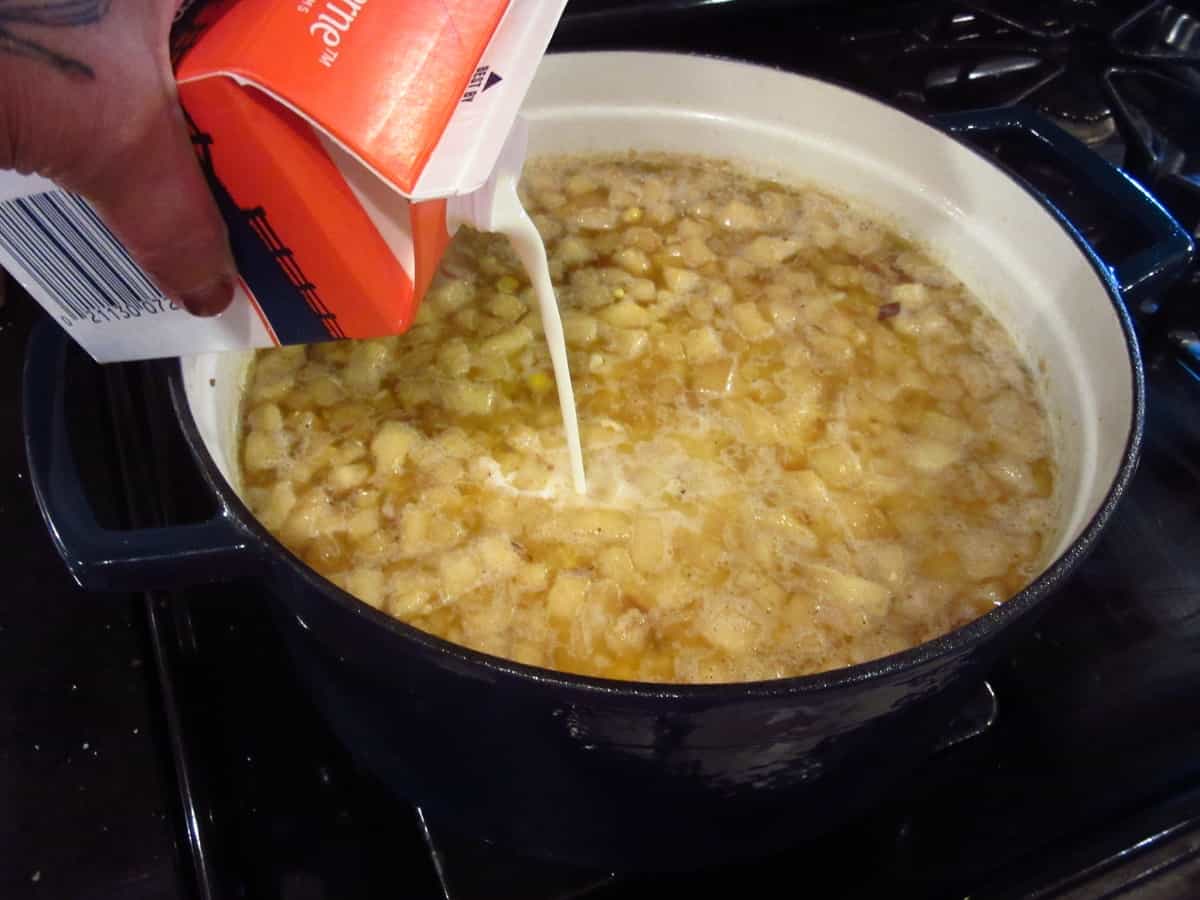 How to make apple corn chowder. Adding heavy cream to the pot as the final ingredient.