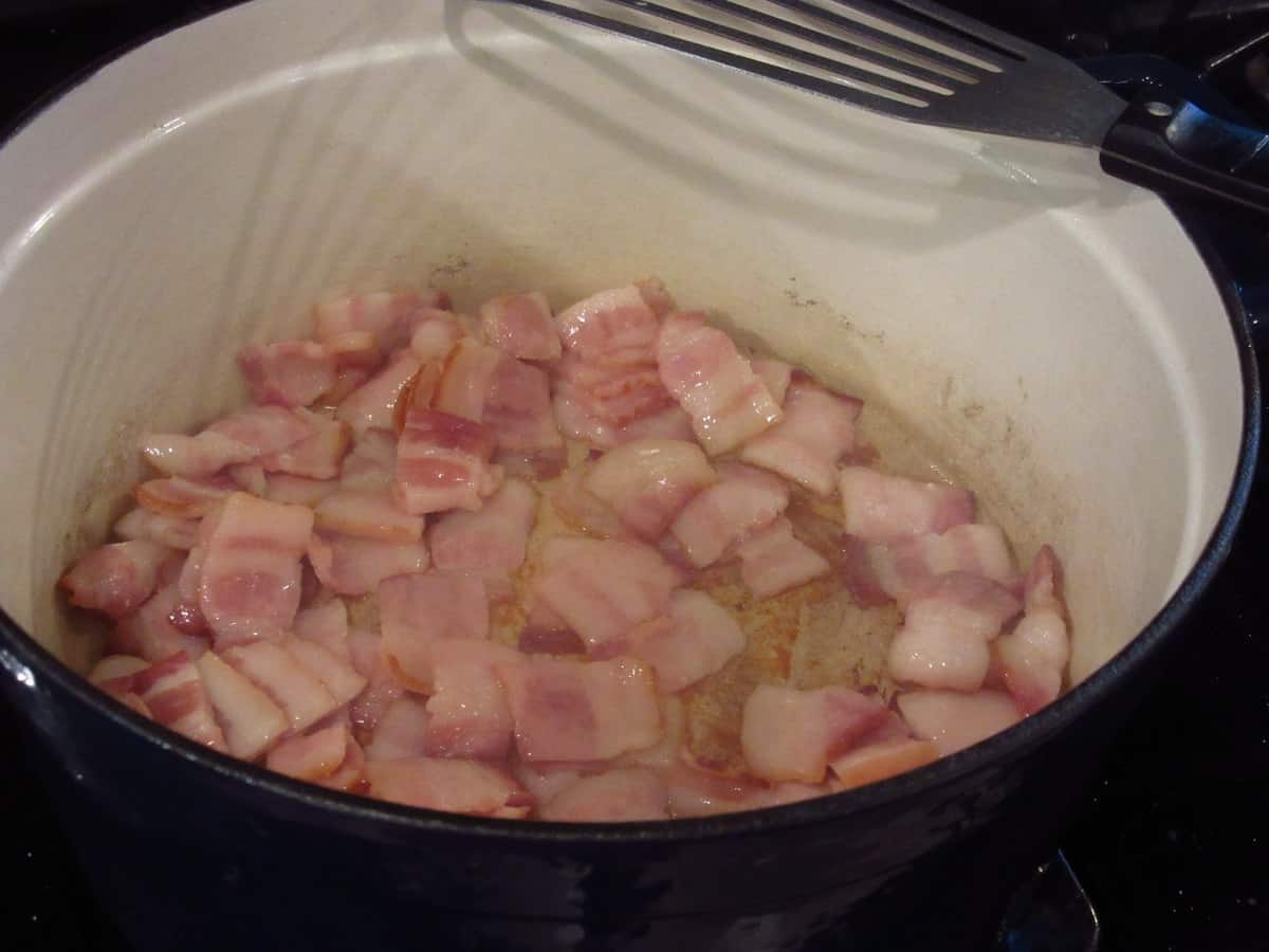 Cut bacon frying in a Dutch oven.