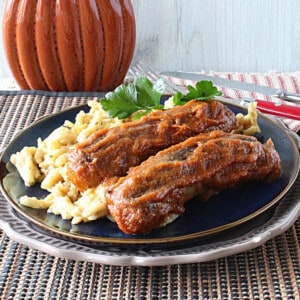 Two pumpkin curry bratwurst on a blue plate with a parsley garnish.