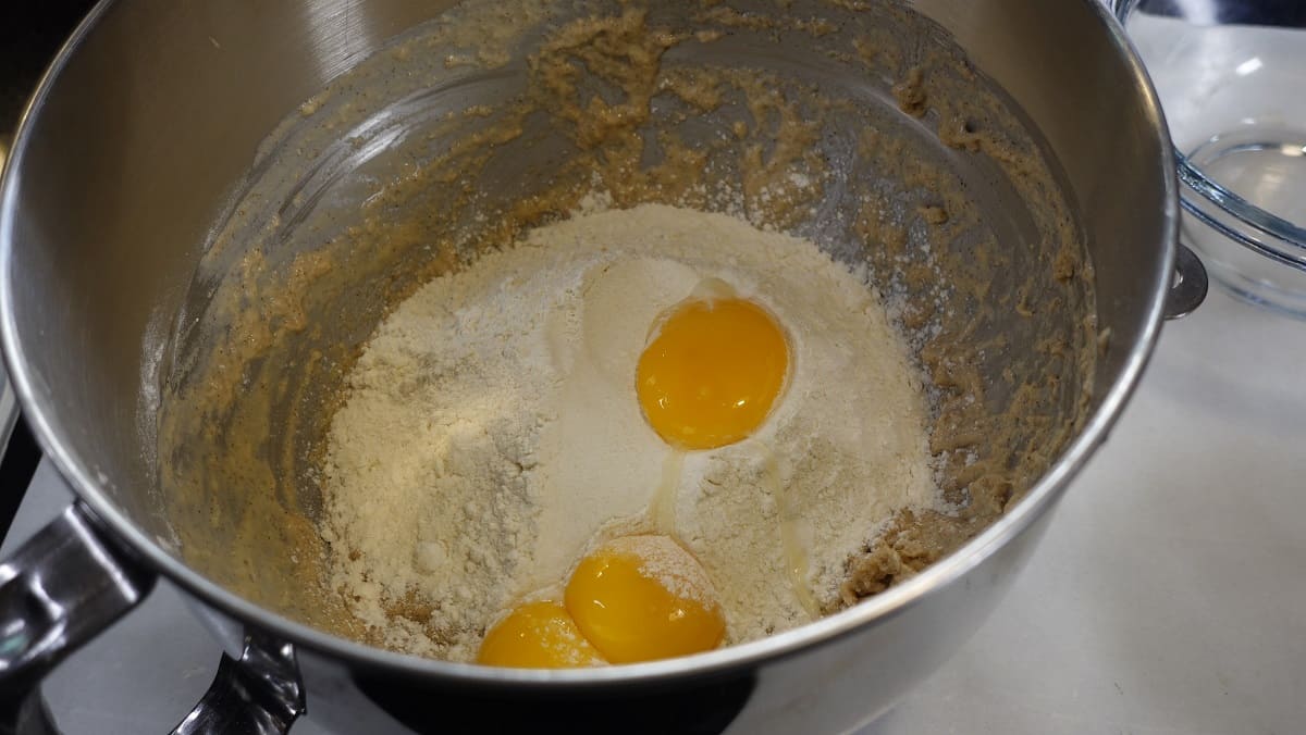 Egg yolks and additional flour being added to a bowl for making yeast donuts.