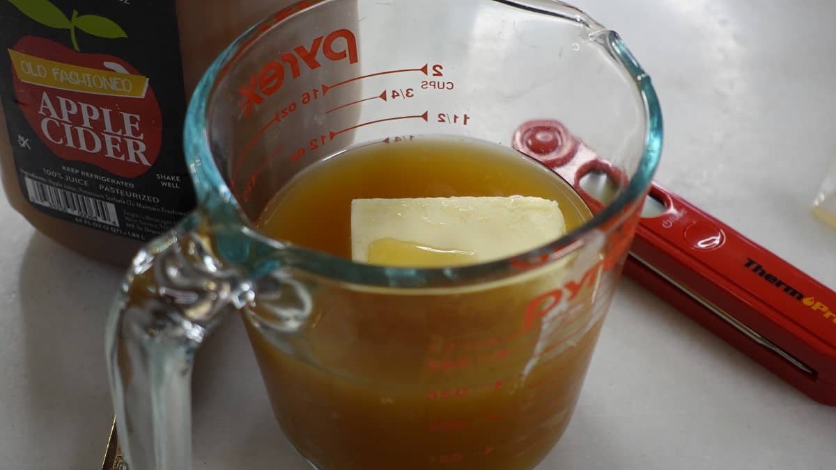 Apple cider and butter in a glass measuring cup.