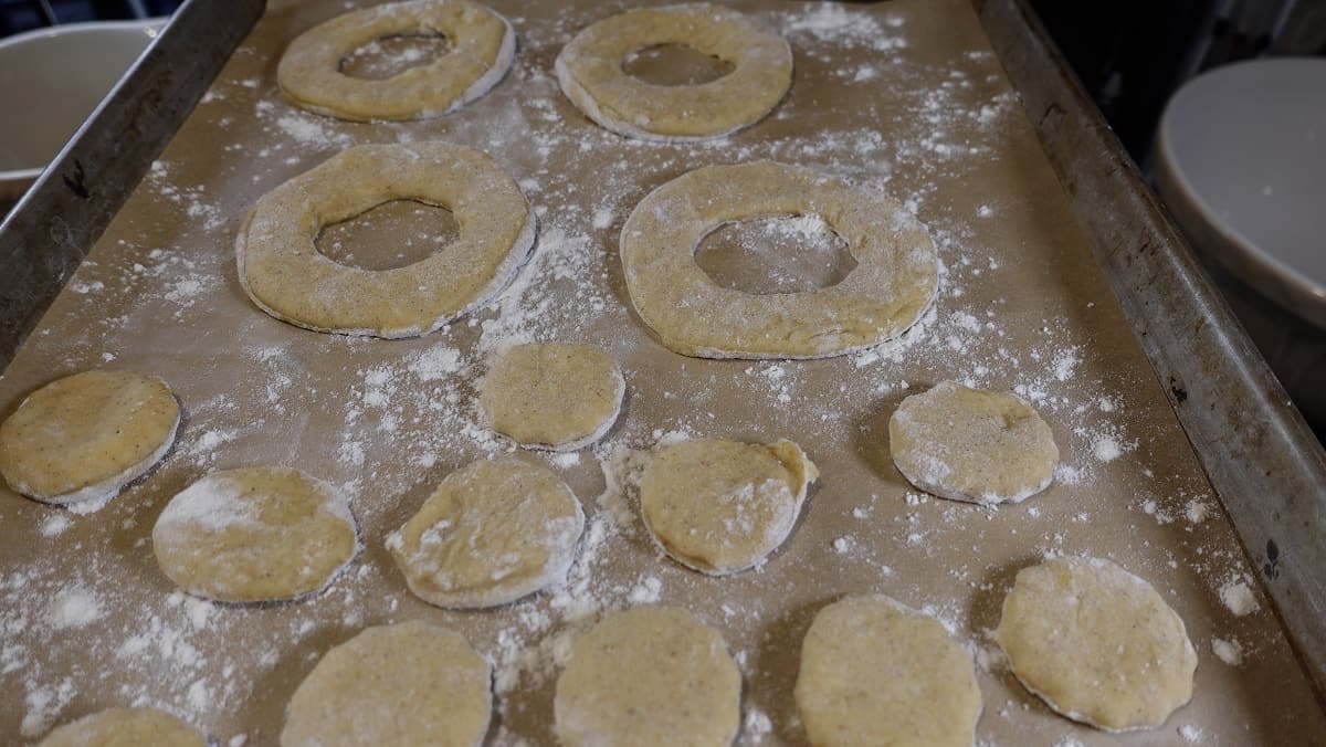 Apple cider donuts and donut hole dough on a baking sheet ready for second proof.