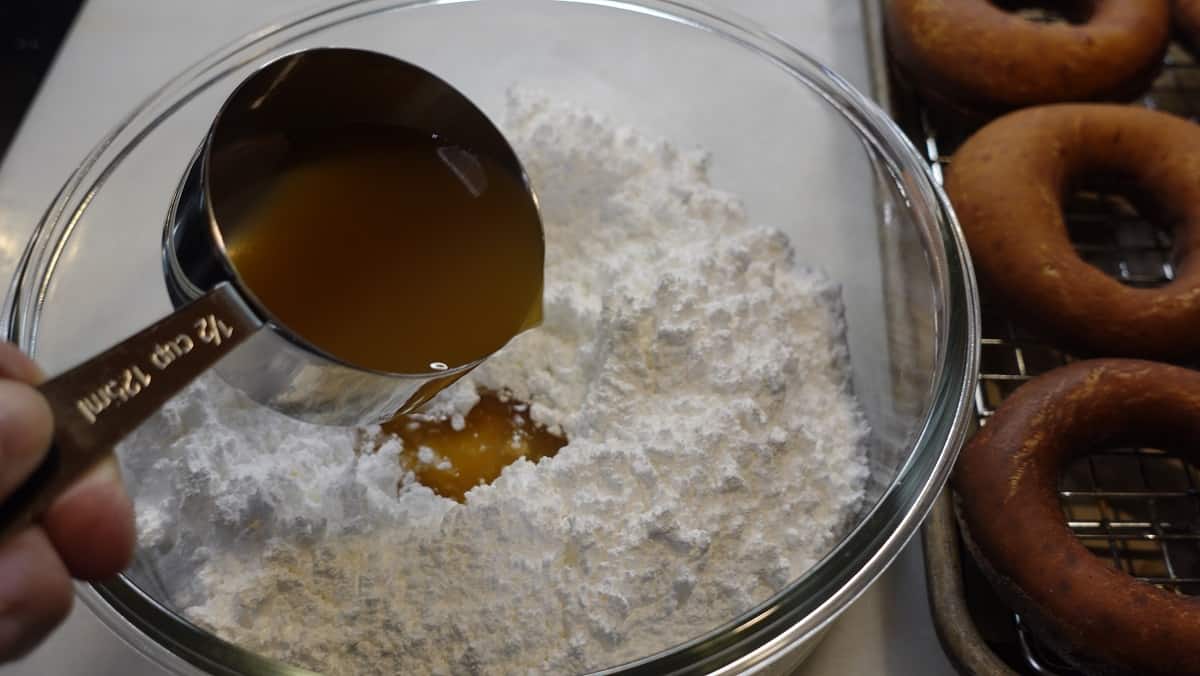 Making a doughnut glaze with confectioners sugar and apple cider.