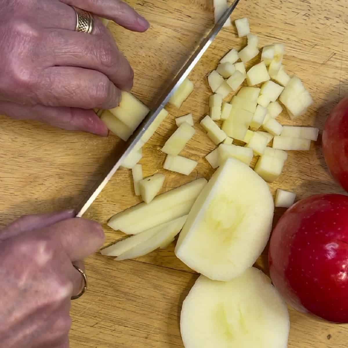 A hand and knife dicing apples for making apple turnovers.