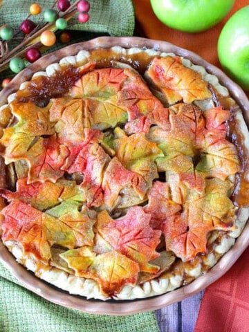 A colorful AUTUMN LEAVES APPLE PIE topped with pie crust leaves in fall colors.