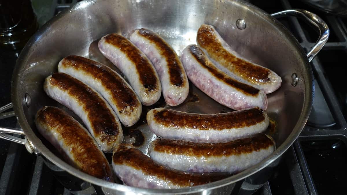 A skillet filled with pan seared bratwurst.