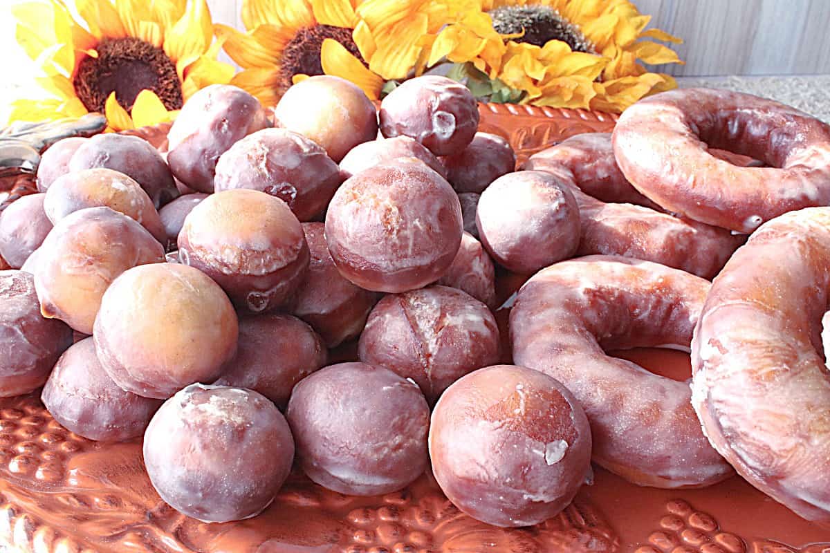 An orange platter piled high with Glazed Apple Cider Donuts and donut holes.