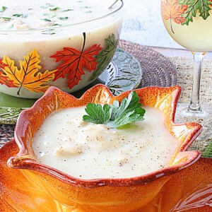 A serving of Creamy Leftover Turkey Soup with Potatoes in a pretty leaf bowl and a parsley sprig.