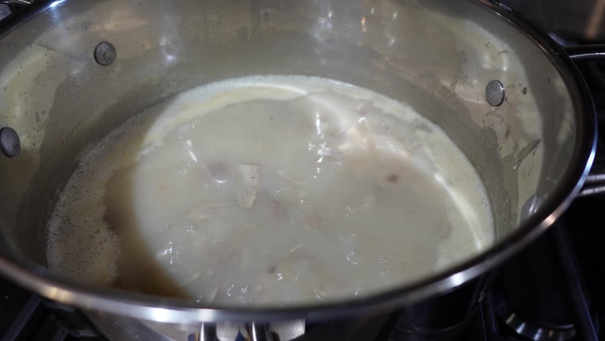 Turkey potato soup coming to a simmer in a saucepan.