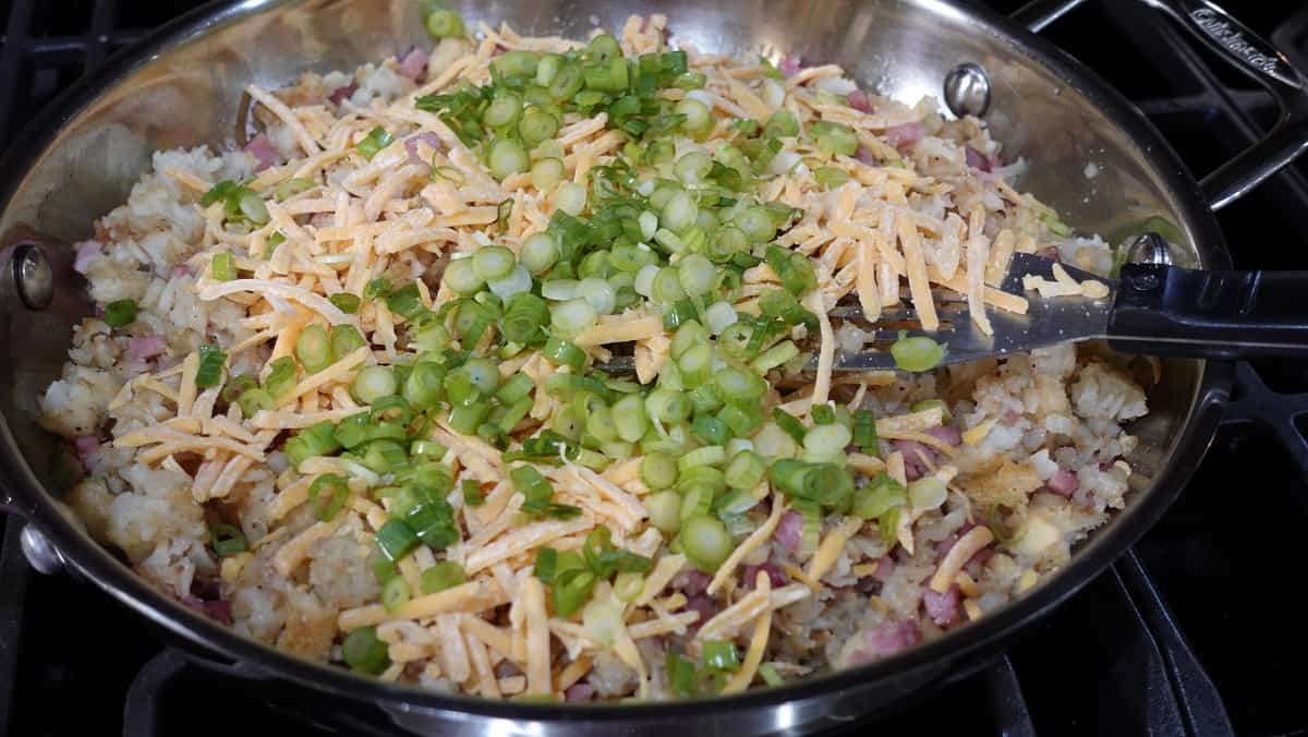 Chopped scallions in a skillet to make a breakfast bake with tater tots.