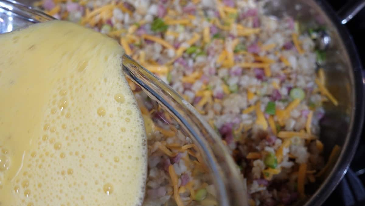 Scrambled eggs being poured into a skillet for a frittata.