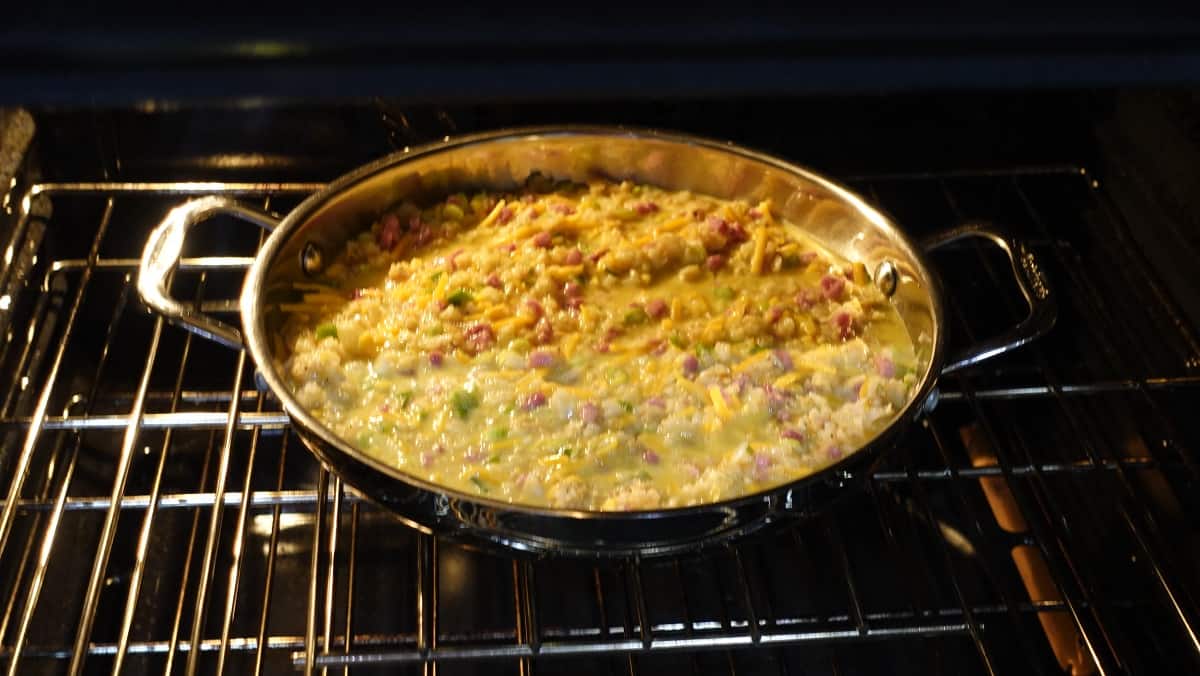 A sauté pan in an oven filled with eggs and potatoes.