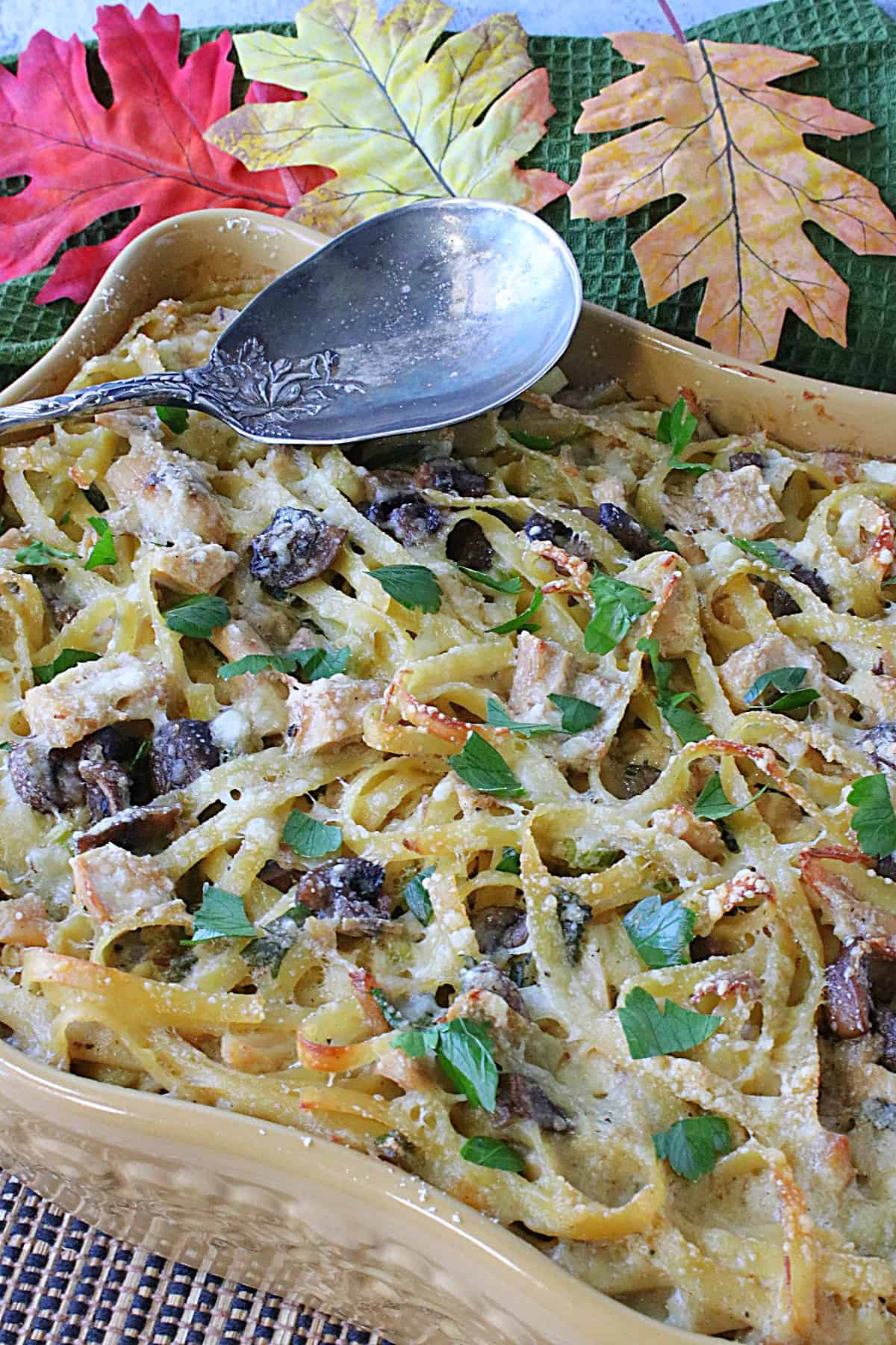 A casserole dish filled with leftover turkey and linguine and topped with parsley.