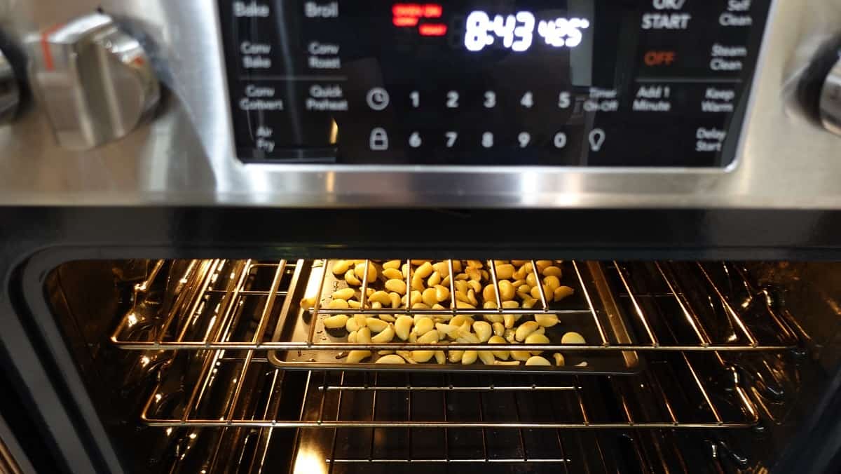 A baking sheet of garlic cloves in an oven.