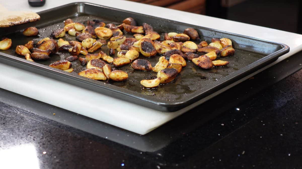 A bunch of roasted garlic cloves on a baking sheet.